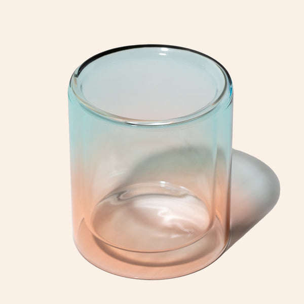 Gradient glass candle holder on a beige background