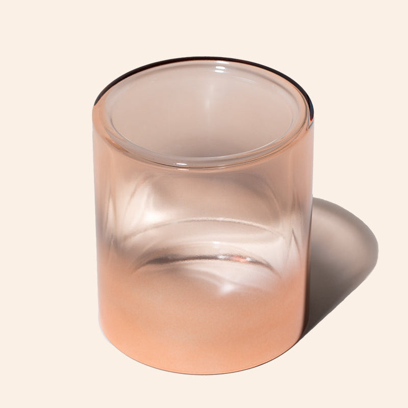Gradient glass candle holder on a beige background