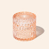 Decorative pink glass candle holder on a light beige background