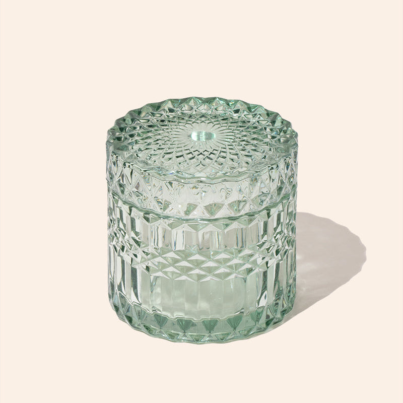 Green textured glass jar on a light beige background