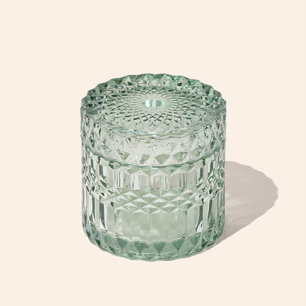 Green textured glass jar on a light beige background