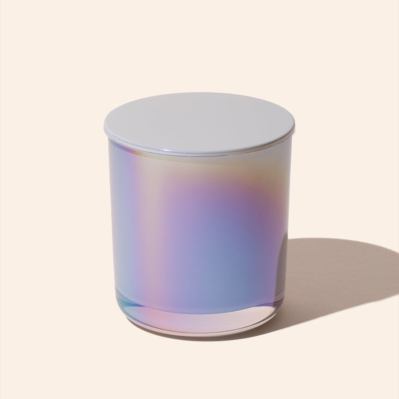 Iridescent glass candle on a light beige background