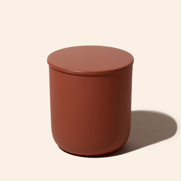 Round terracotta-colored container with lid on a beige background