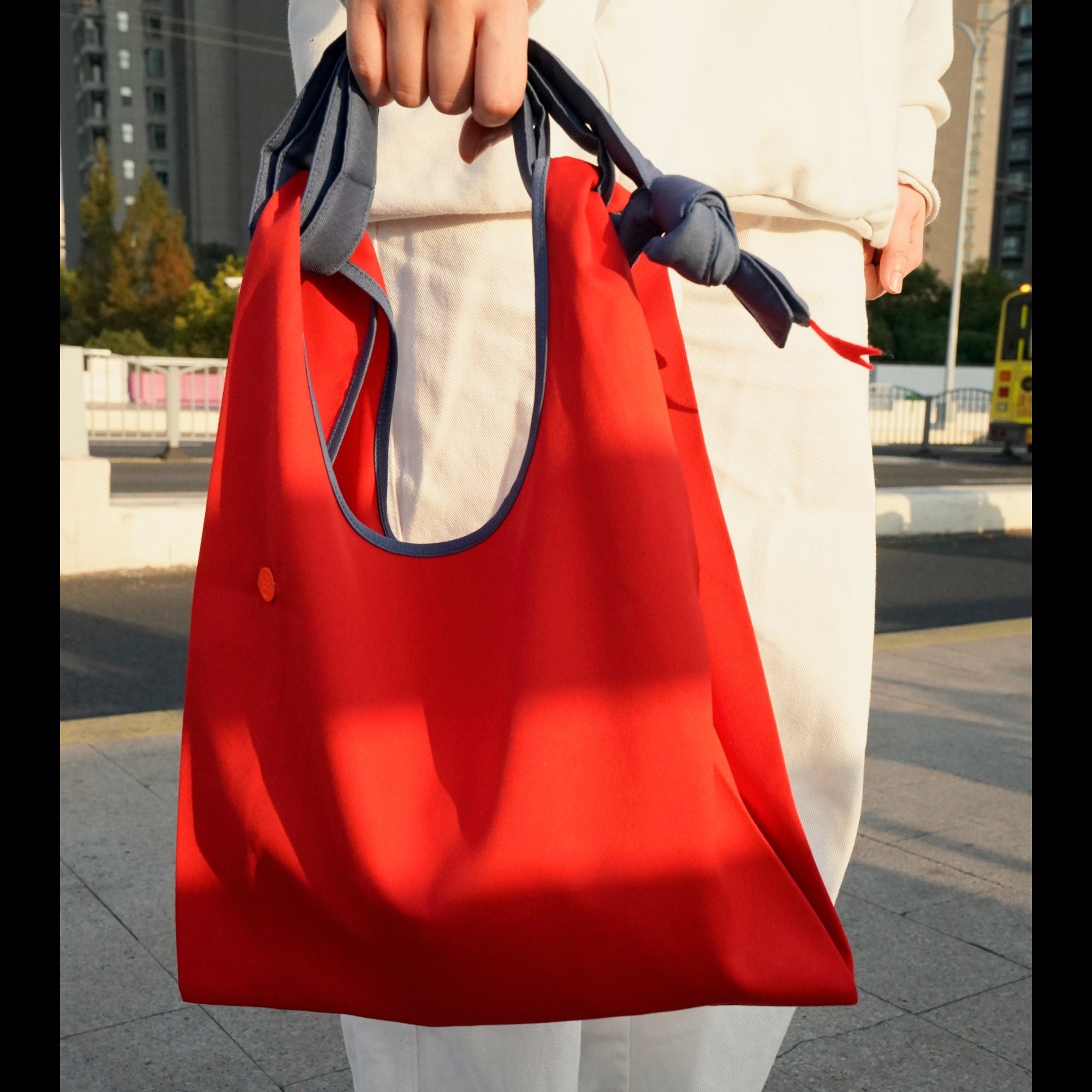 Person holding the HowBottle Little Snake Lunar New Year limited edition red recycled bag in an urban setting