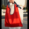 Person holding the HowBottle Little Snake Lunar New Year limited edition red recycled bag in an urban setting
