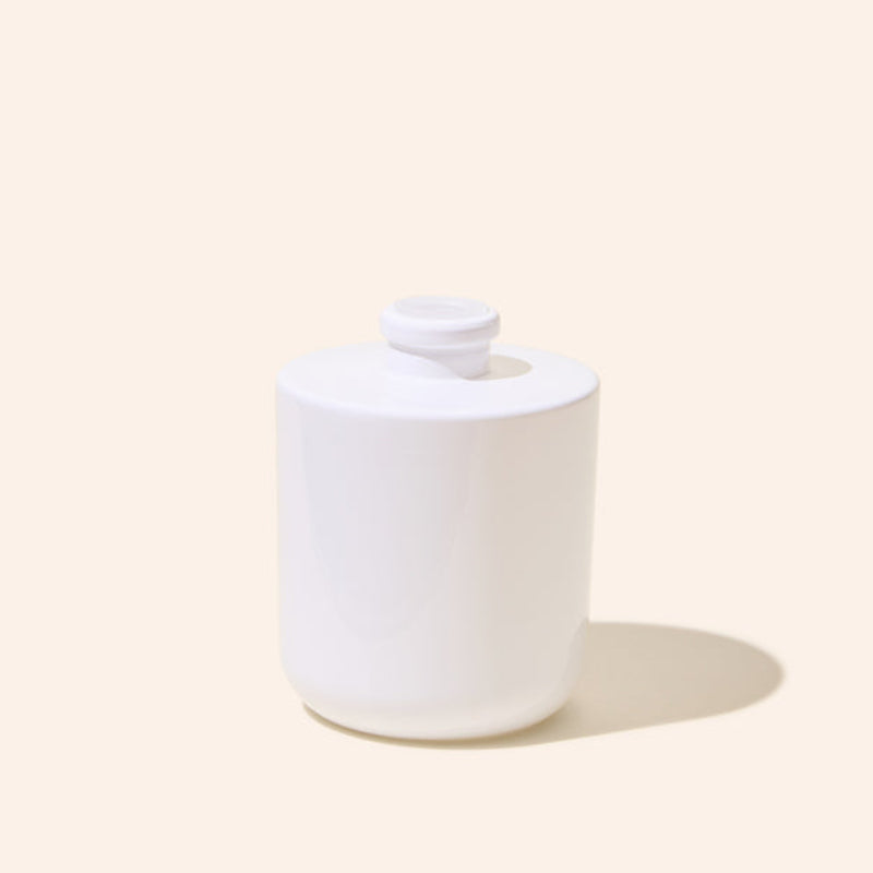 White ceramic jar with a lid on a beige background