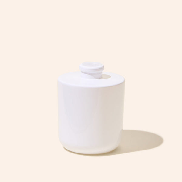 White ceramic jar with a lid on a beige background