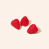 Three red raspberries on a light pink background