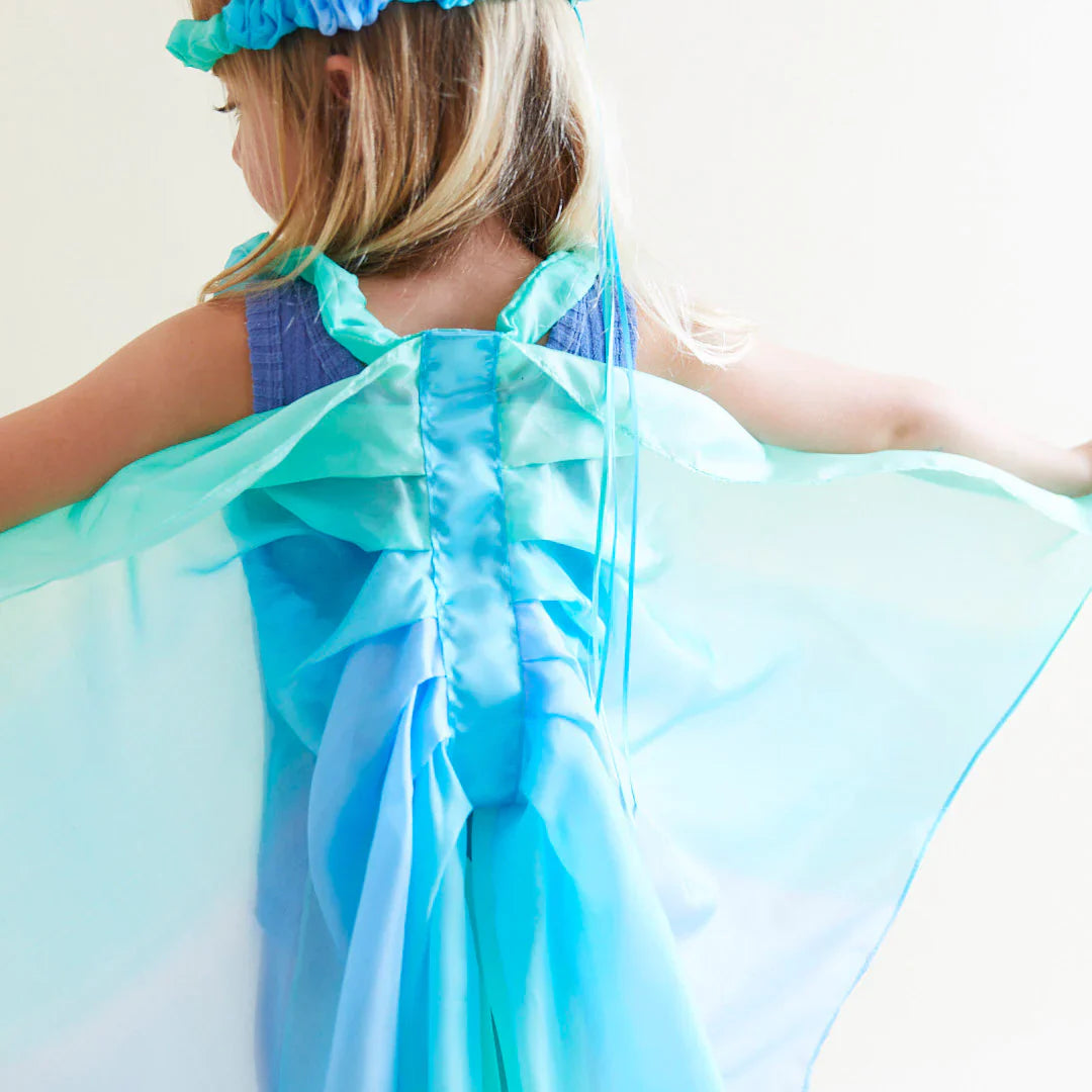 Child wearing a blue dress with a matching cape and headband against a white background