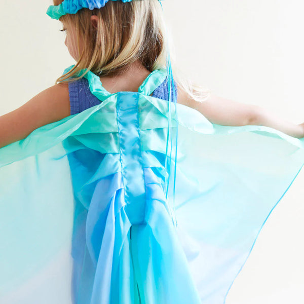 Child wearing a blue dress with a matching cape and headband against a white background