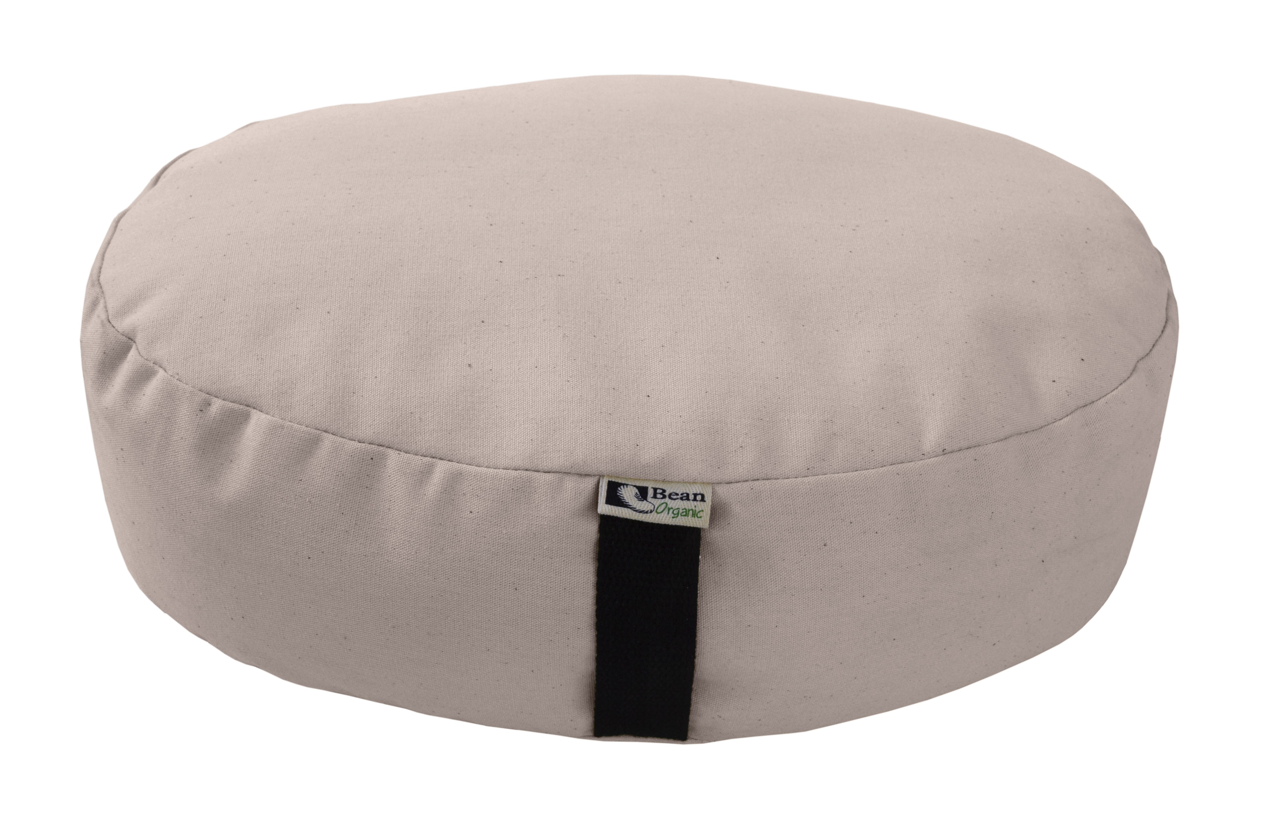 Beige meditation cushion with a black strap on a white background