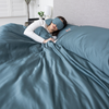 Person lying in bed with blue bedding and a matching eye mask.