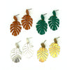 Fair Anita monstera leaf stud earrings in silver-plated recycled metal on a flat lay surface