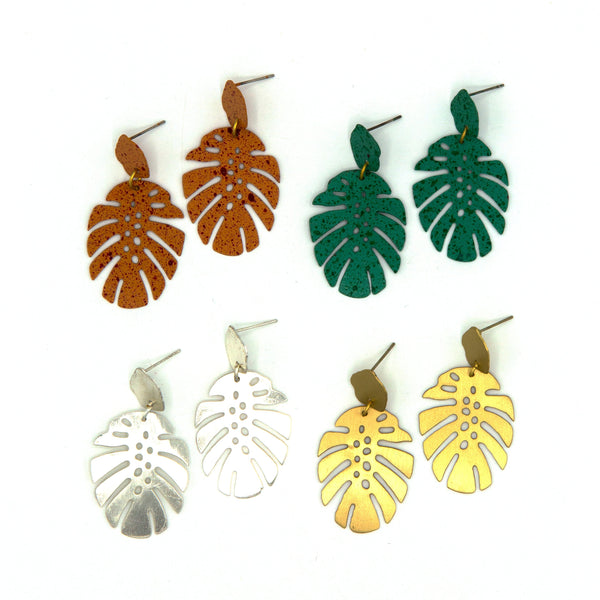 Fair Anita monstera leaf stud earrings in silver-plated recycled metal on a flat lay surface