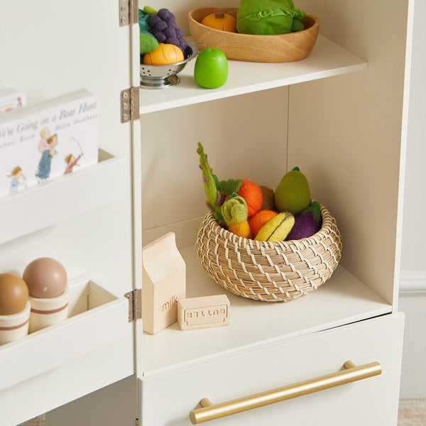 Play food fruit and vegetables in a wicker basket displayed on the Tiny Land wooden play kitchen fridge shelf
