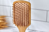 Desesh plastic-free bamboo hair brush laying flat, highlighting natural wood grain and wide paddle shape