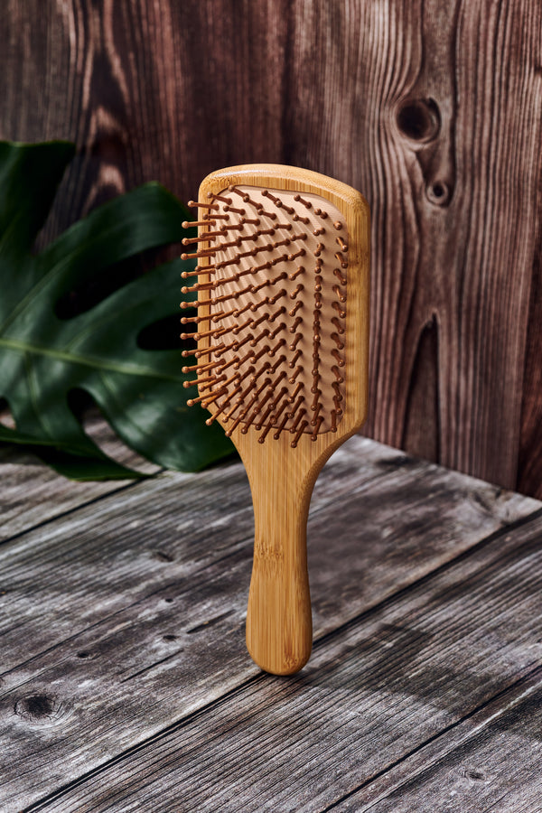 Desesh bamboo paddle hair brush in use, detangling and smoothing hair naturally