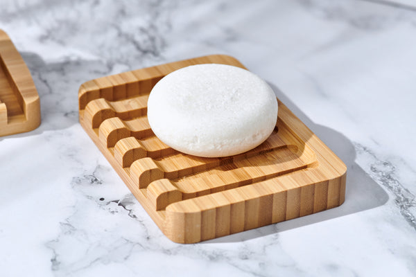 Eco-friendly bamboo soap dish holding a bar soap on a shower or bathtub shelf