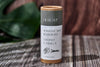 Deosesh sensitive skin deodorant container on a wooden surface with green leaves in the background