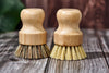 Desesh bamboo handle-less dish brush being used to scrub a dish at the kitchen sink