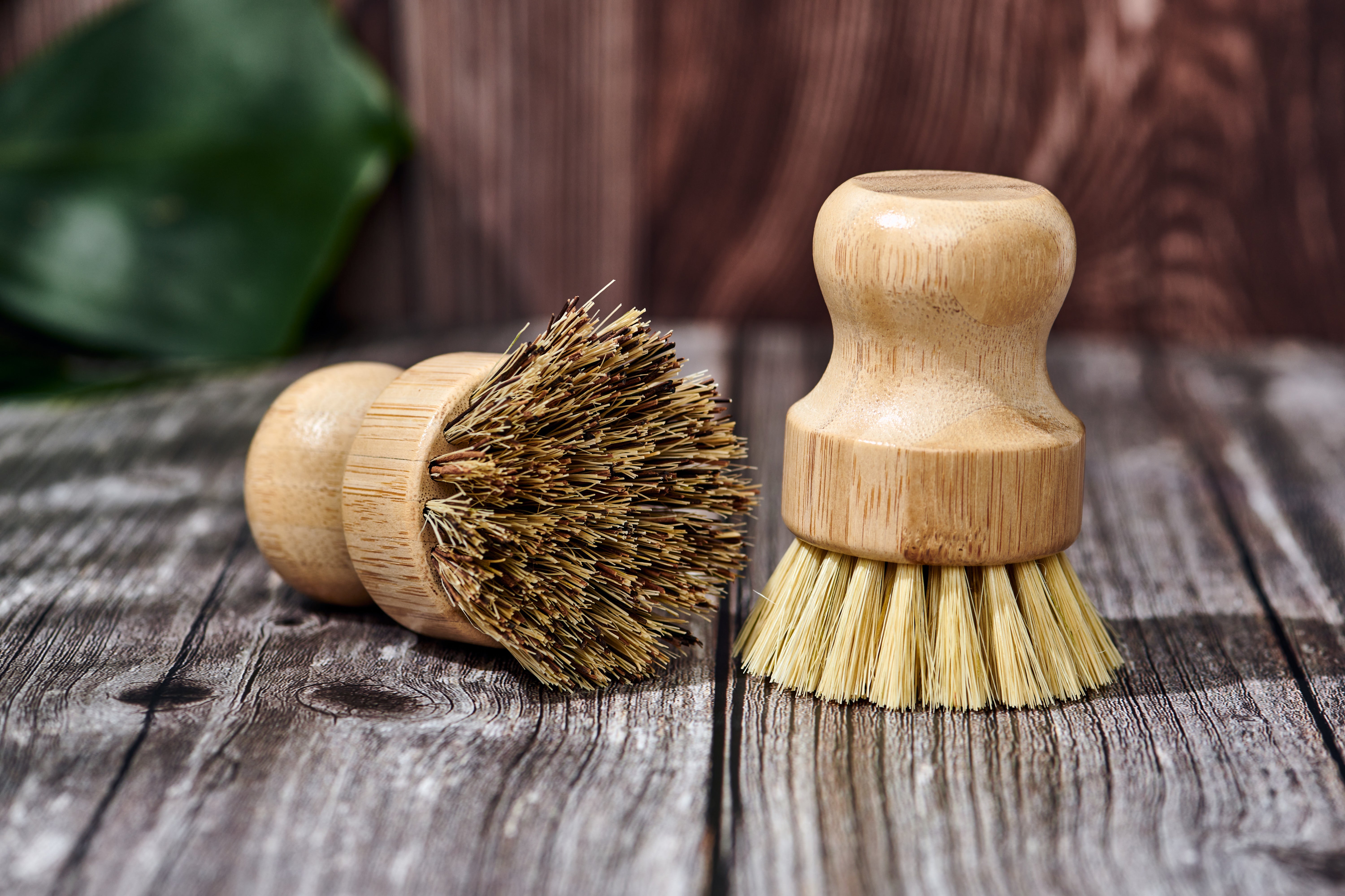 Desesh bamboo dish scrubbing brush resting on plastic-free paper packaging on a wooden surface