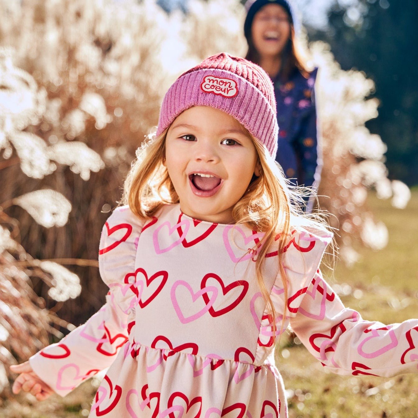 Baby wearing Mon Coeur long sleeve ruffle dress with heart print in recycled cotton