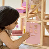 Child playing with a wooden dollhouse and pink door