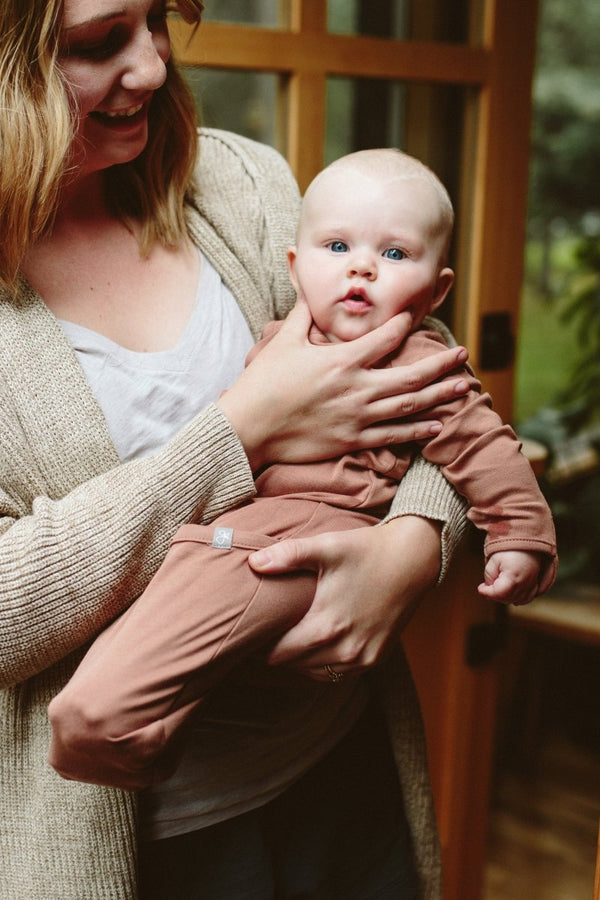 Woman holding a baby in a warm, indoor setting