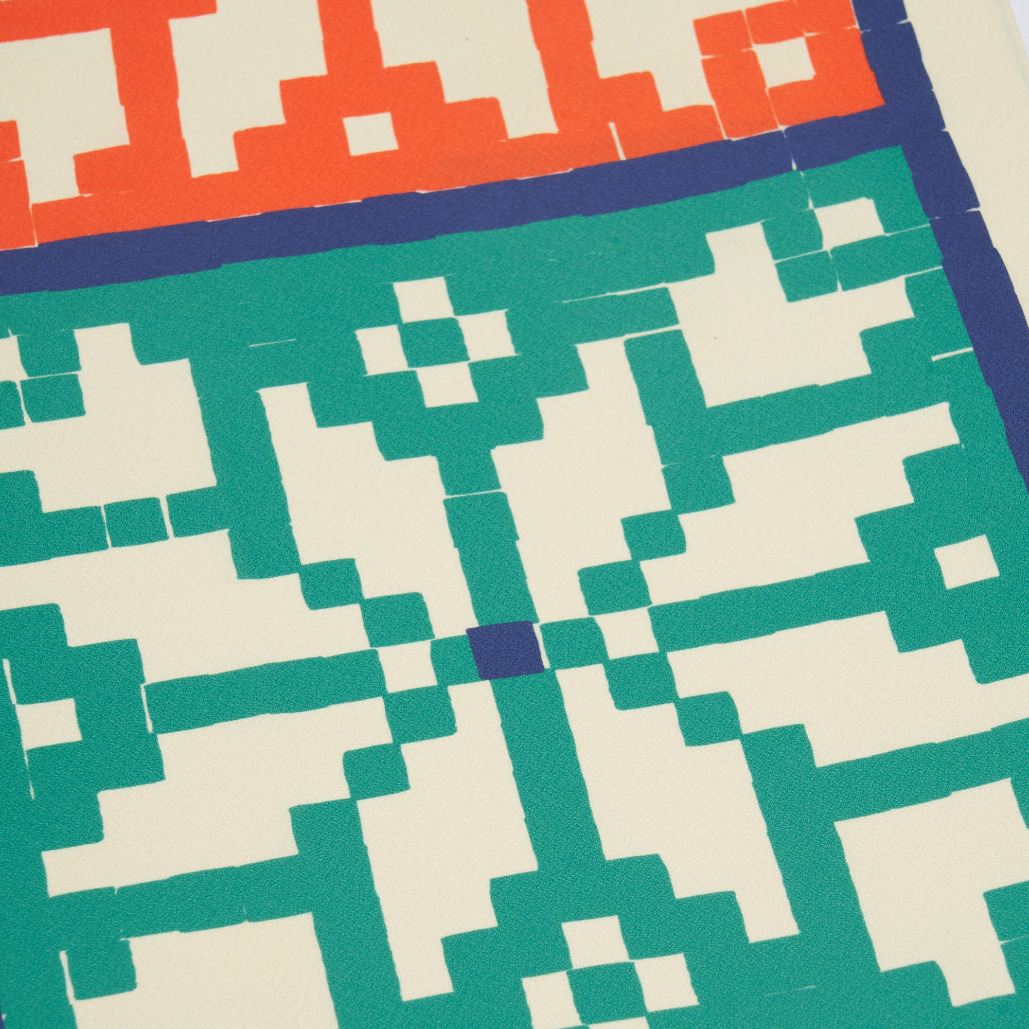 Close-up of a quilt with geometric pattern in green, white, and blue on a beige background.