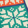 Close-up of a quilt with geometric pattern in green, white, and blue on a beige background.