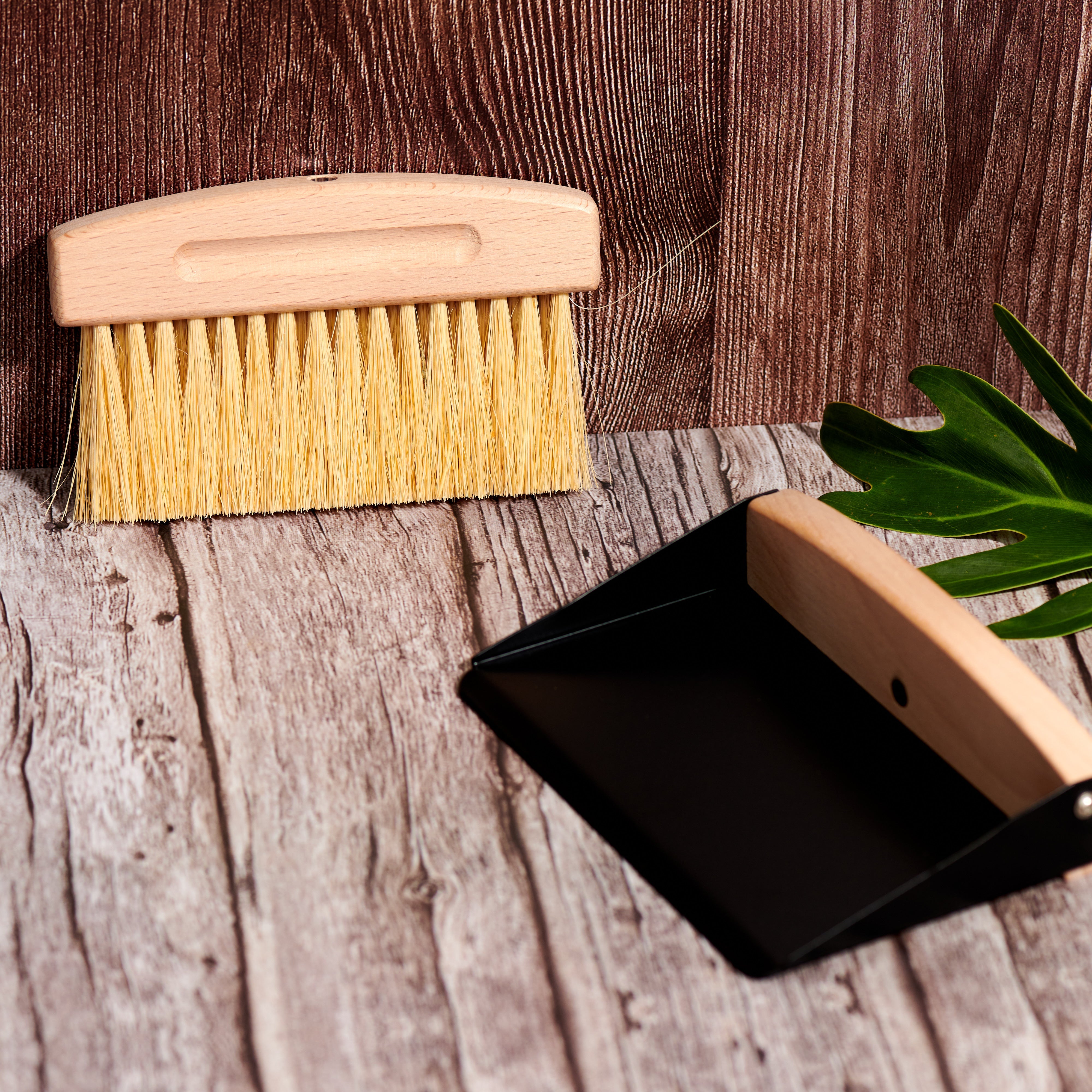 Close-up of Desesh mini wood broom with natural sisal bristles and black metal dustpan