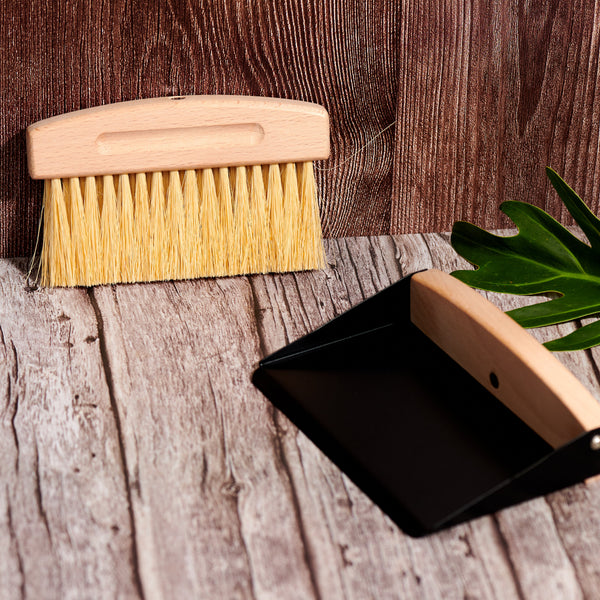 Close-up of Desesh mini wood broom with natural sisal bristles and black metal dustpan