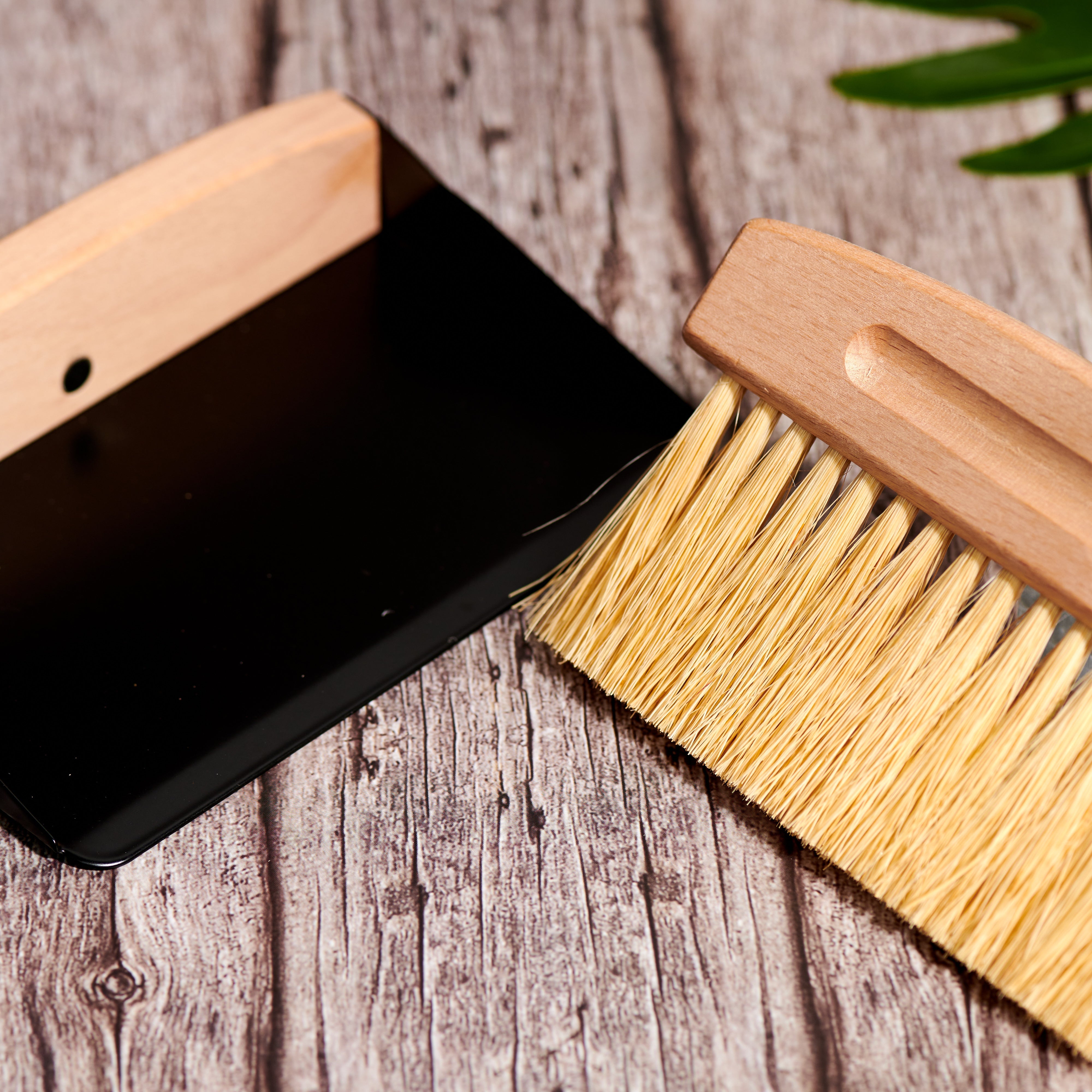 Detail shot of natural wood handle and sisal bristles on Desesh mini broom and black dustpan set