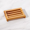 Natural bamboo soap dish next to bar soap and eco-friendly bathroom accessories