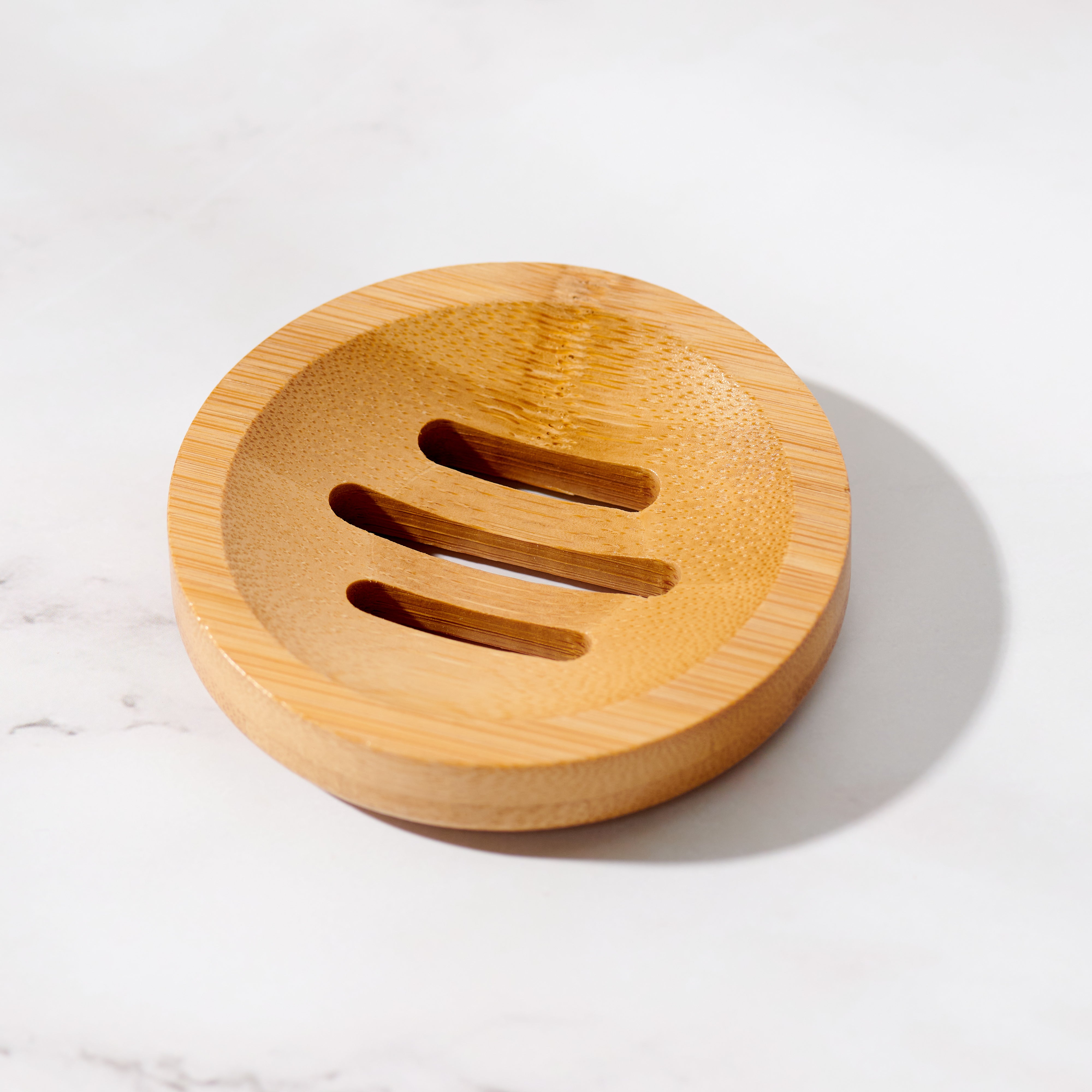 Bamboo circular soap dish beside a bar of soap in a minimal bathroom setting
