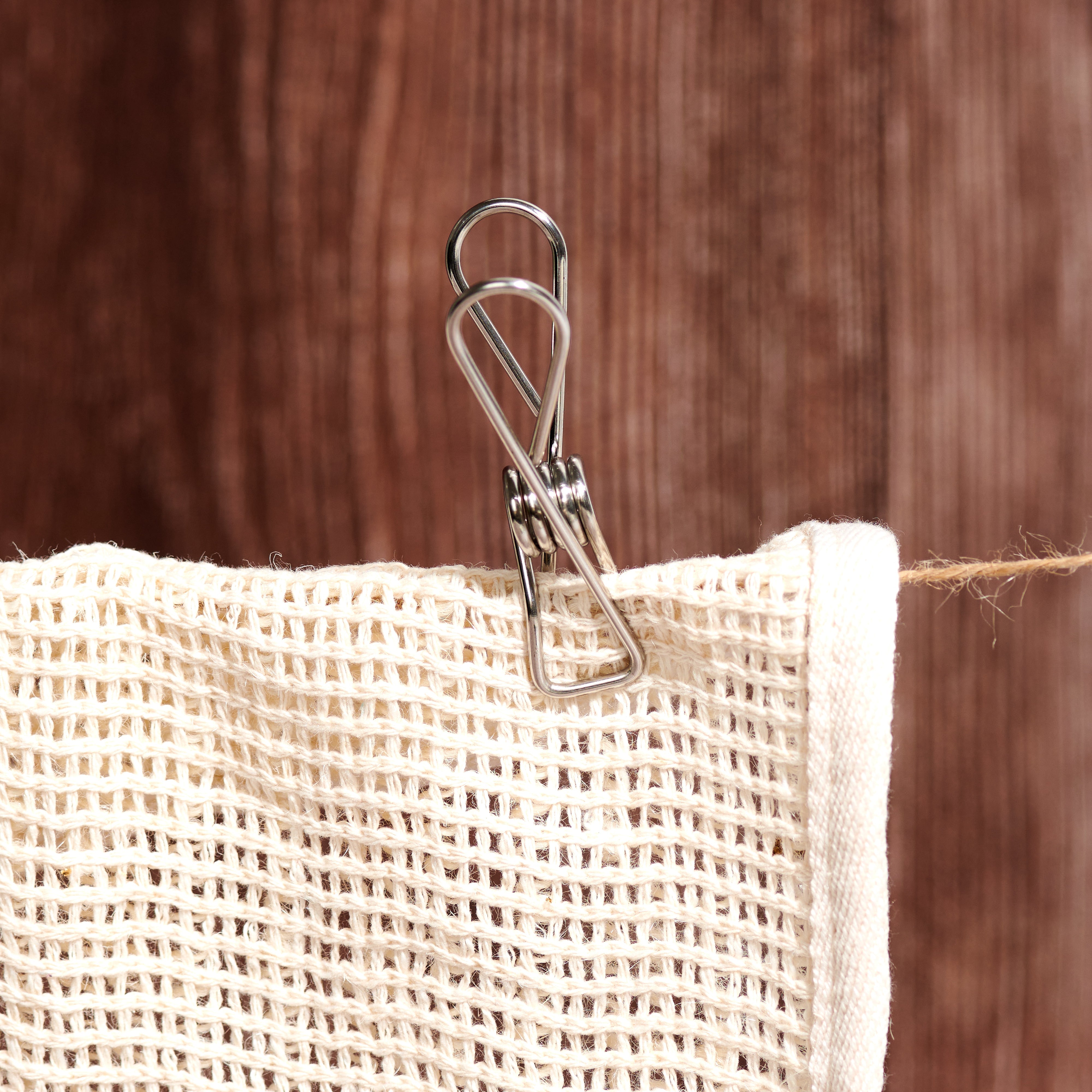 Stainless steel pegs stored inside a natural cotton mesh drawstring bag, approximately 7 x 5.5 inches