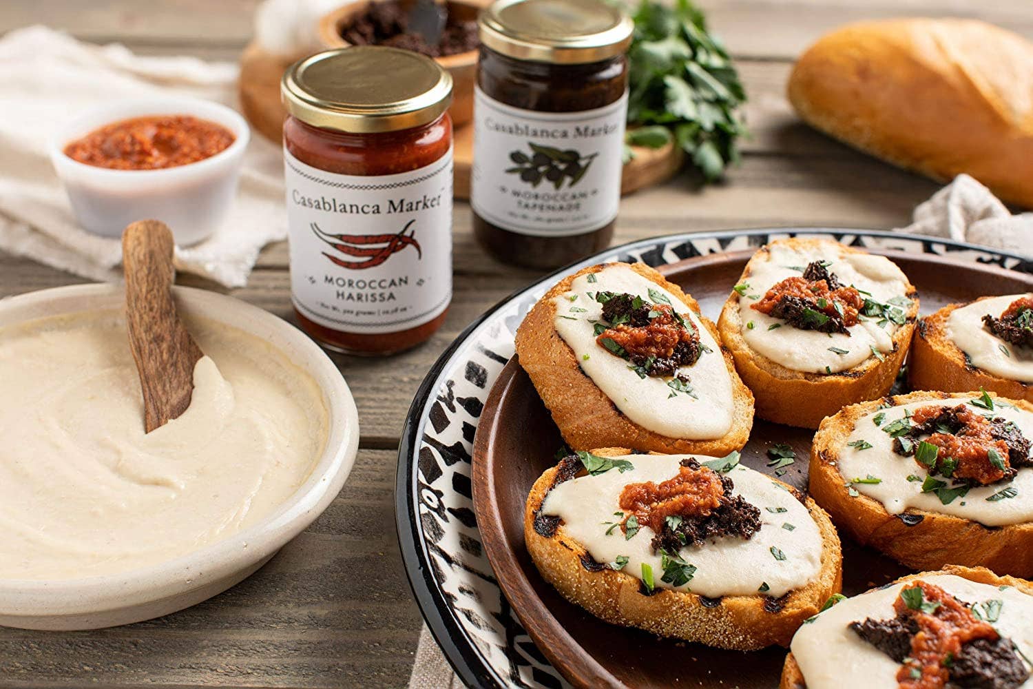 Small sandwiches with spread and tapenade on a plate, accompanied by jars of Presidencia Marroquina tapenade and bread.