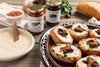 Small sandwiches with spread and tapenade on a plate, accompanied by jars of Presidencia Marroquina tapenade and bread.