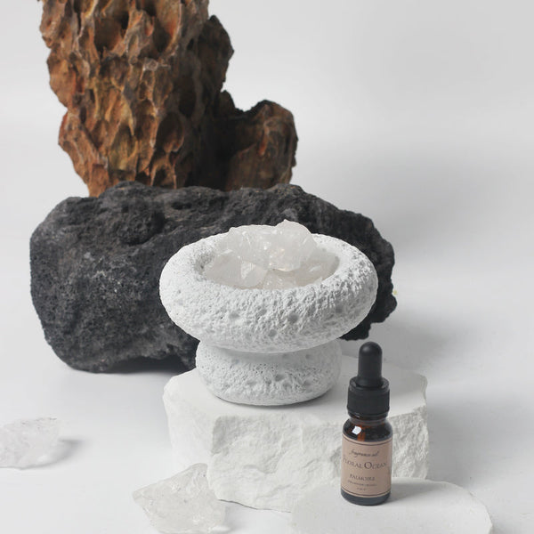 Decorative stone bowl with a bottle of essential oil on a white background
