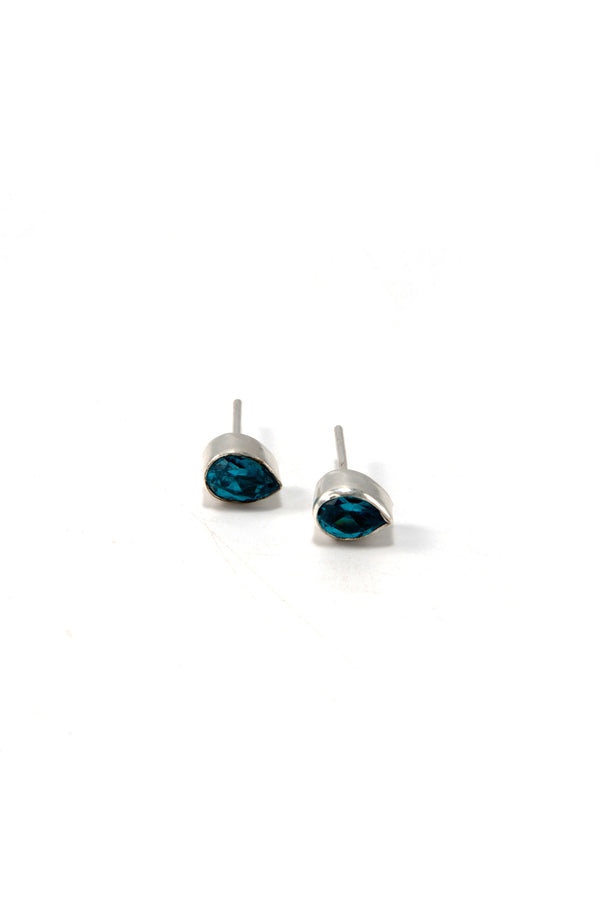 Flat lay of faceted teardrop stud earrings in pink and blue zircon on neutral background