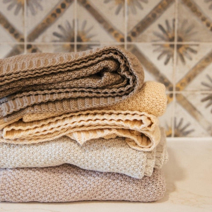 Macadamia knitted cotton swaddle blanket folded in nursery setting