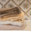 Macadamia knitted cotton swaddle blanket folded in nursery setting