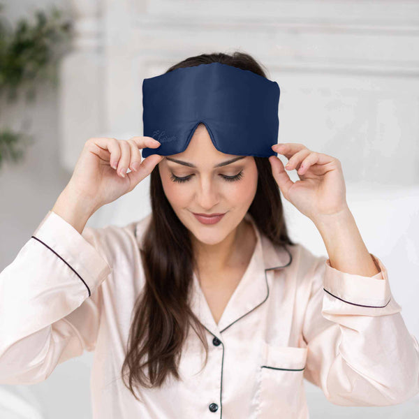 Woman wearing a blue sleep mask with a blurred indoor background