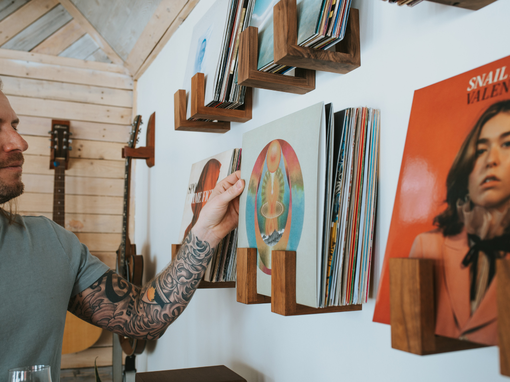 Person selecting a vinyl record from a wall-mounted hardwood Flip Record Display Shelf
