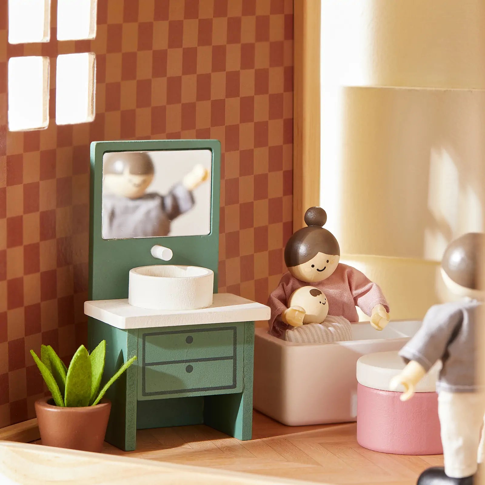Wooden dolls and furniture set in a room with a checkered wall.