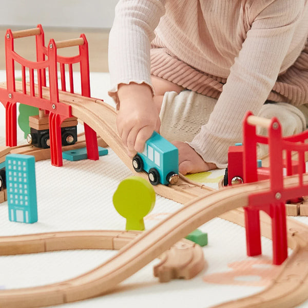 Child playing with a wooden train set on a light surface
