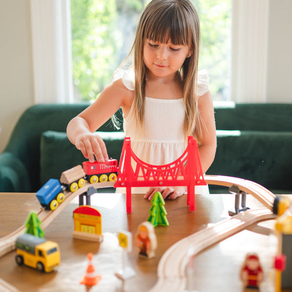 Young girl playing with a toy train set on a table.