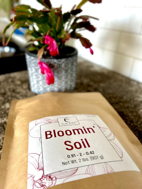 Bag of Bloomin' Soil with a plant in the background