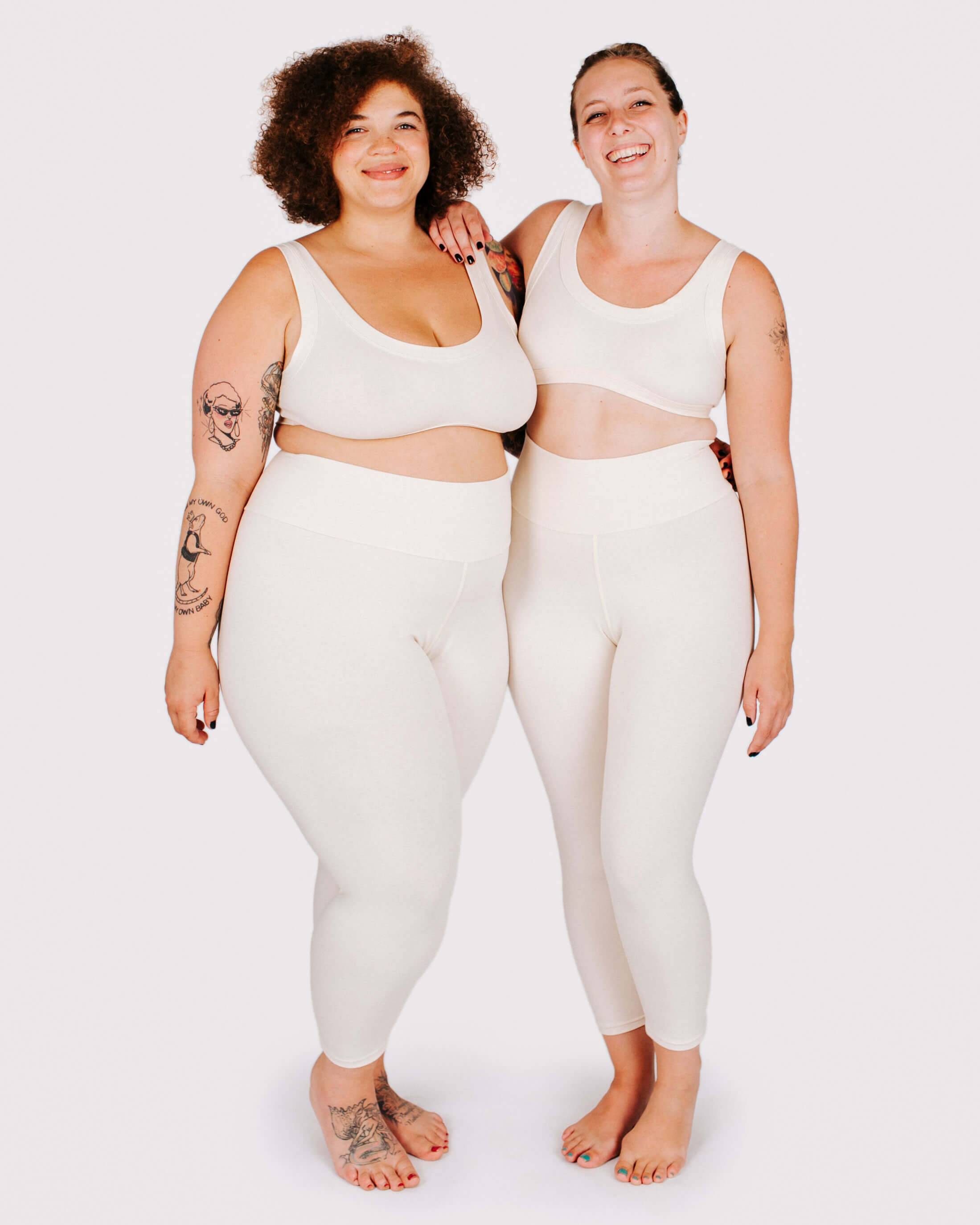 Two people wearing matching white athletic outfits on a plain background