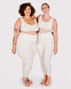 Two people wearing matching white athletic outfits on a plain background